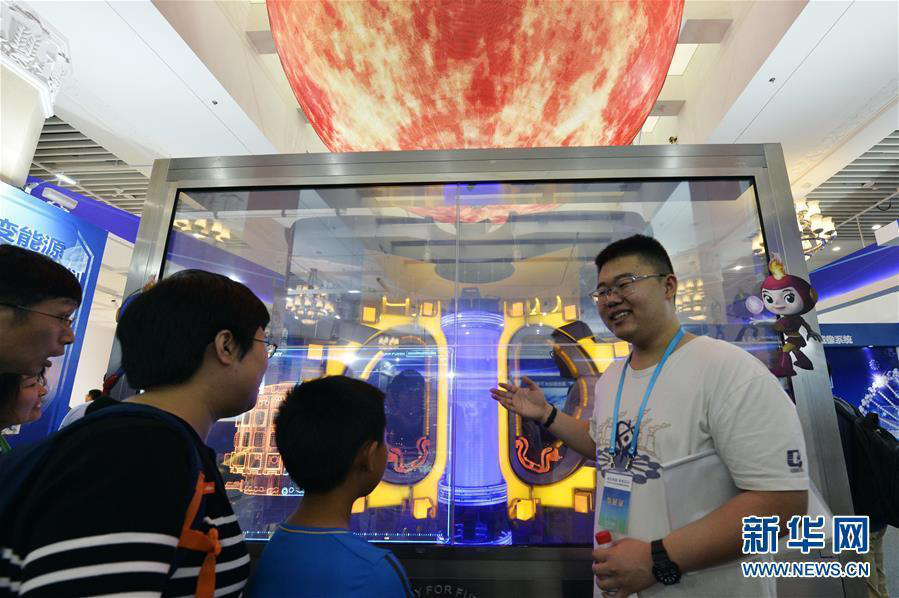  2018全国科技活动周暨北京科技活动周上，工作人员为观众介绍核聚变装置。来源：新华社