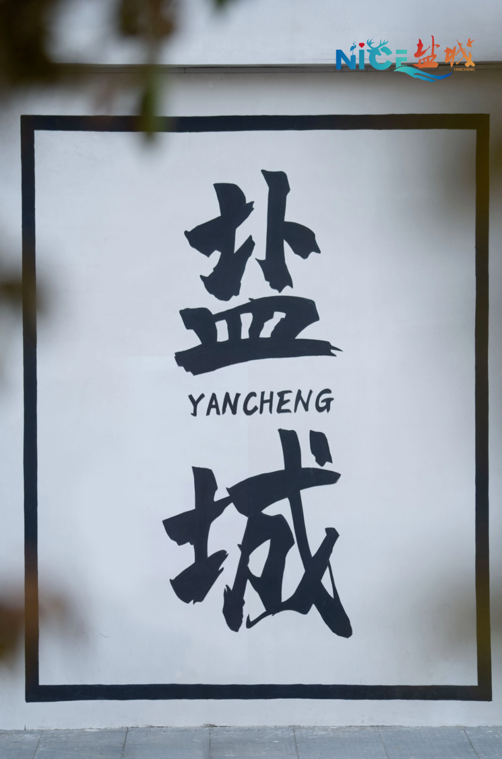 一整面大墙上书「盐城」二字在这么一幅能撑起整个镜头的墙壁前你站在