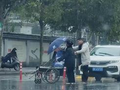 老人雨中过马路，暖心车主飞奔送伞，一路口车静静等待